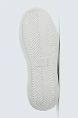 Zapatillas deportivas negras con detalle en blanco en el talón y suela blanca con volumen.