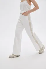Pantalón jean de calce ancho y tiro alto, con diseño color block en tonos blanco y beige.