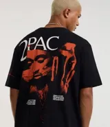 Remera negra de algodón con corte relaxed, cuello redondo y mangas cortas. Estampa frontal con una cruz y el nombre "Tupac Shakur" en color naranja.