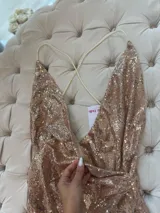 Vestido corto dorado de lentejuelas con escote en V profundo, tirantes finos cruzados en la espalda y cierre invisible.