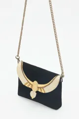 Cartera de mano negra de cuero gamuzado con solapa bordada con diseño de alas en tonos dorados y plateados. Tiene cierre magnético, bolsillos internos y cadena metálica dorada vieja.