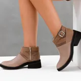 Bota corta de cuero color marrón con cierre lateral, suela de goma negra y hebilla decorativa.