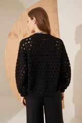 Chaqueta tipo bomber de punto negro, con diseño calado y cierre frontal.
