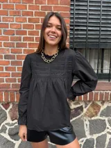 Camisa blanca de mangas largas con detalles de encaje en el cuello y el pecho.