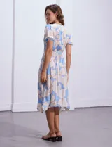 Vestido midi estampado con flores color celeste y beige, escote cruzado, mangas cortas con puños elastizados, cintura elastizada con lazo de ajuste.