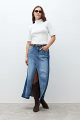 Falda larga de jean de tiro alto, con lavado medio y tajo frontal profundo. Presenta un diseño bicolor con paneles de denim de tonos ligeramente diferentes.