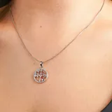 Collar plateado con dije circular calado con forma de árbol de la vida y pequeños brillantes incrustados.