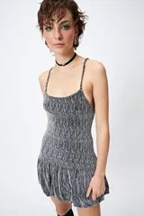 Vestido corto de lurex plateado y negro, sin mangas, con breteles finos regulables y volados tipo balloon desde la cadera.