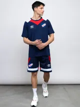 Remera de fútbol Umbro del Club Nacional de Football, modelo de entrenamiento. Diseño azul con detalles en blanco y rojo en cuello y mangas. Incluye logo de Umbro y escudo del club en el frente.