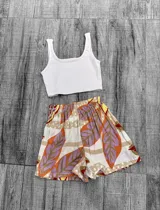Short de tela con estampado de hojas en colores vibrantes como naranja y rosa, con cintura elástica.