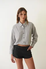 Camisa corta negra de algodón, de corte holgado, con cuello camisero y abotonada al frente.