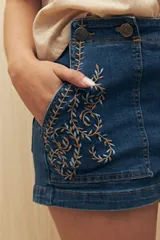 Short de jean azul con bordado floral en los bolsillos delanteros.