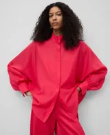 Camisa blanca de manga larga, con cuello chimenea alto y botonadura frontal oculta. El tejido es semitransparente y presenta una textura ligera.