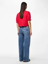 Blusa roja con estampado floral, escote en V con lazos, mangas cortas abullonadas con volantes en los puños y corte cropped.