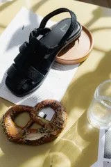 Sandalias de cuero marrón con diseño de tiras entretejidas y hebilla lateral.