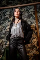 Chaqueta negra de gamuza con cuello camisero, cierre frontal con botones y bolsillos laterales.