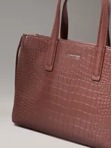 Cartera tote de piel sintética con textura de cocodrilo, de diseño compacto con asas y cierre de cremallera.