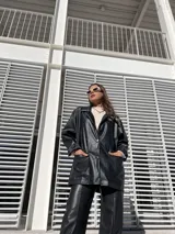 Blazer oversize de ecocuero color negro, con mangas largas con botón (tipo camisa) y bolsillos amplios delanteros.
