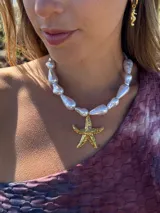Collar corto con cuentas simil perla y dije de estrella de mar dorada. Se cierra con cadena y ganchito para regular el largo.