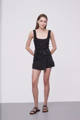 Short de jean negro con corte asimétrico y cierre con botón.