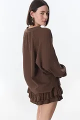 Camisa beige de manga larga con botones y detalles de encaje.
