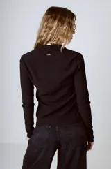 Camisa negra de tejido texturizado con cuello camisero, manga larga y cierre frontal con botones.