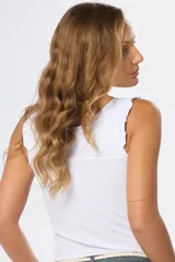 Musculosa blanca de algodón con cuello redondo, breteles anchos con volados y cierre parcial con botones.