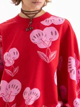 Buzo rojo de calce amplio, confeccionado en tela de punto con estampado de cerezas en color rosado. Presenta cuello redondo, puños y bajo en tejido liso a tono.