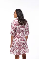 Vestido corto camisero blanco con estampado de motivos campestres en color bordó. Tiene cuello camisero, mangas 3/4, lazo en la cintura y volado en el ruedo.