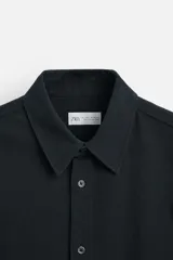 Camisa azul marino de algodón con textura jacquard, corte relaxed fit, cuello solapa, manga larga con puños abotonados y cierre frontal con botones.