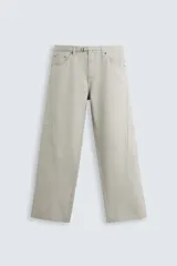 Pantalón de algodón color beige claro, estilo relaxed fit, con cintura ajustable mediante cinturón de tela a juego. Presenta cinco bolsillos, bolsillos laterales de vivo y costuras laterales giradas hacia adelante.