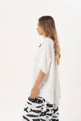 Camisa blanca con calados, escote en V, abotonada y manga 3/4.