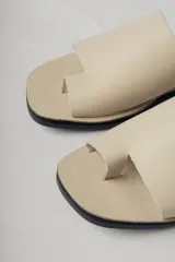 Sandalias planas de cuero color negro, con tira ancha sobre el empeine y diseño minimalista.