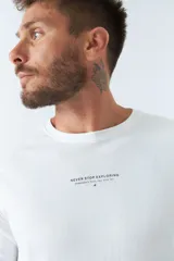 Remera blanca de manga larga con cuello redondo y logo estampado en el pecho.