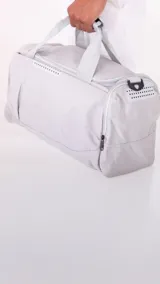 Bolso deportivo gris de nylon con doble asa y correa regulable. Cuenta con dos bolsillos exteriores con cierre, un bolsillo exterior de rejilla y un bolsillo interior con cierre.