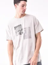 Remera blanca de corte recto con estampa fotográfica de edificios en la parte frontal.