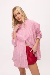 Camisa oversize a rayas verticales color amarillo y blanco, con cuello camisero, manga larga y cierre frontal con botones.