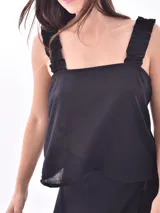 Blusa sin mangas color amarillo pálido, con breteles anchos con volados y escote cuadrado.