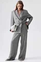 Pantalón de vestir gris claro, de tiro alto, con bolsillos laterales y traseros. Piernas amplias con pliegues delanteros y traseros. Confeccionado en tejido liviano de mezcla de lino y viscosa.