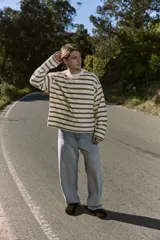 Buzo de manga larga color crudo con rayas horizontales color verde oliva, de corte oversize cropped y cuello redondo.