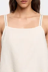 Vestido midi de algodón y lino color crudo, corte línea A con vuelo y bajo irregular. Presenta escote recto con tirantes finos y top superpuesto con bordados a contraste.