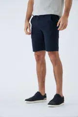 Bermuda color beige de corte chino, con bolsillos laterales, cierre con cremallera y botón, presillas para cinturón y logo bordado. Confeccionada en lino y algodón.