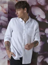 Camisa blanca de lino con cuello clásico, manga larga con puños abotonados y bolsillo de parche en el pecho. Corte recto.