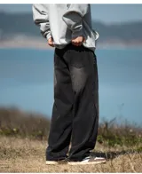 Jean de mezclilla color negro lavado, corte ancho y holgado, caracterizado por costuras diagonales pronunciadas en la parte delantera de las piernas que crean un efecto de paneles o cortes asimétricos.