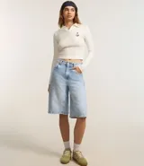 Blusa de manga larga color crema, con cuello polo, escote en V y bordado de ancla en el pecho.