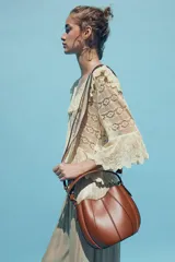 Bolso marrón formato saca con asa de mano y tira bandolera extraíble. Incluye cartera con bolsillo extraíble y cierre mediante botón imantado.