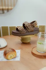 Sandalias de cuero color marrón con plataforma forrada en cuero y hebillas doradas.