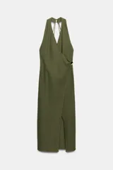 Vestido midi color verde oliva confeccionado en lino. Presenta escote pico cruzado, tirantes anchos delanteros y tirantes finos en la espalda, detalle de aplique dorado en la cintura, bajo con abertura frontal y cierre lateral con cremallera oculta.