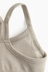 Top deportivo color beige de tejido acanalado con tecnología DryMove™ que absorbe el sudor. Tiene breteles finos, espalda nadadora, copas forradas con relleno extraíble y bajo elástico acanalado.