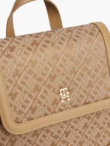 Mochila Tommy Hilfiger color beige con monograma de la marca en jacquard. Tiene asa superior, correas ajustables, cierre de solapa, compartimento principal y detalles distintivos de la marca.